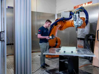 A student uses the robot arm in the engineering design and manufacturing centre