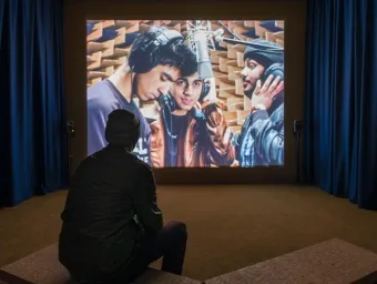 A young man watching an audio-visual art piece at the John Hansard art gallery.