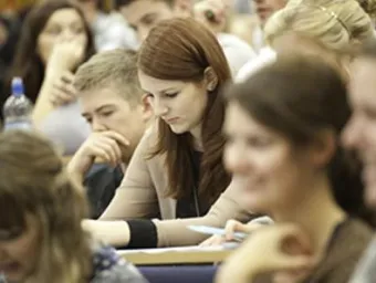 A postgraduate researcher concentrating on her notes during a seminar.