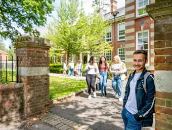 A student smiling at the gates of avenue campus