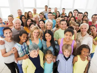 A stock photo of a large group of people of all ages, genders and ethnicities smiling up at the camera.