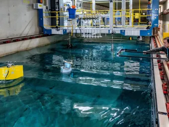 A student uses the 138m towing tank to investigates a buoy's hydrodynamic performance while a researcher offers advice