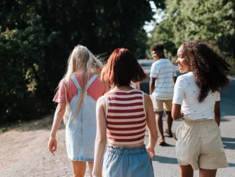 Teenagers walking down a sunny country lane away from the camera