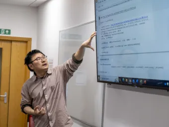 Business analytics teacher Libo Li points at information on a screen during a class