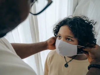 A patient looks up as a medical professional puts a clinical mask onto them