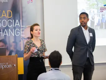 A speaker at a University of Southampton talks to an audience, with a 'Social Impact Lab' slide displayed above them