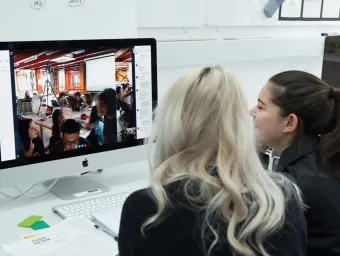 Two design students work on a studio project together, viewing visuals on a desktop computer