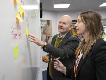 Colleagues from Hatch consultancy discussing ideas, using post it notes on a whiteboard