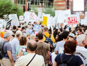 Pexels image of people taking part in a rally, with placards, rucksacks and phones