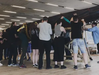 A large group of people lift a boat exhibition into place at Winchester Gallery