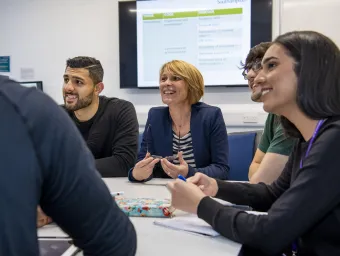 A group of medicine students sit at a table during a class, with Professor Sally Curtis among them