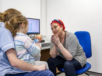 A friendly looking health sciences worker chats to a child patient