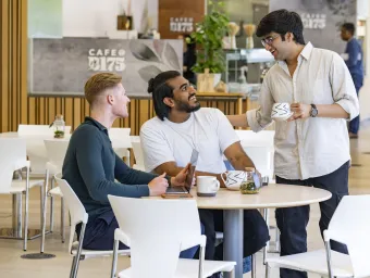 A customer standing talking to 2 customers sitting at a table in B175 Cafe