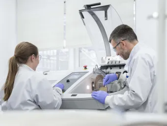 2 researchers placing samples in a scintillation counter.