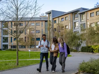 Three students walking outside halls of residence