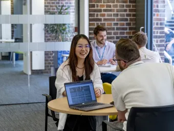 A student discussing fees with a university advisor. Another student and advisor talking are in the background.