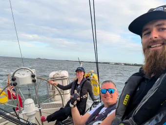 Participants on a sailing session out on the water smiling taking a selfie