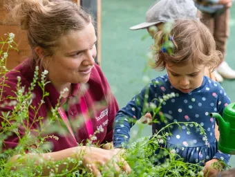 Early Years Centre carer with child watering plants