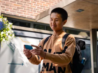 A student holding their ID card while stood outside the entrance to University of Southampton's Student Hub.