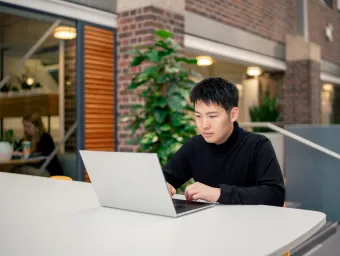 A student sat at a desk in the University of Southampton's Student Hub, with a laptop open on the desk.