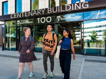 Three students walking outside the entrance to Centenary Building, also known as Building 100, on the University of Southampton's Highfield campus.