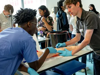 A small group of young people, engaged in a practical medical summer school session to find out what it’s like to be a doctor.