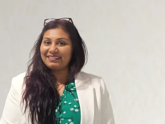 Marilyn D'Costa smiling at the camera, wearing a flowery green top under a white jacket.