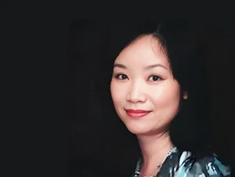 Sylvia Pender looking directly at the camera with a black background.