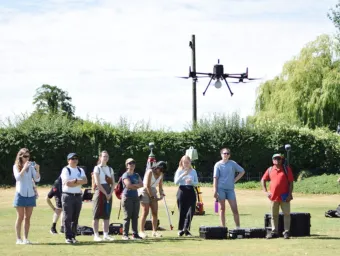 A group of people out on a field using an aerial drone.