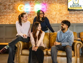 A group of students sat on a sofa socialising.