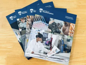 A stack of University prospectuses spread in a fan shape across a table.