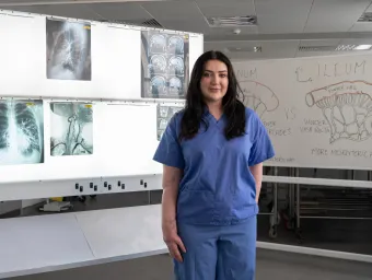 Medical student Becca standing in a teaching room with medical imaging displays.