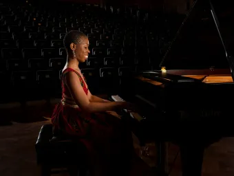 Dr Samantha Ege performing at a grand piano in a concert hall.