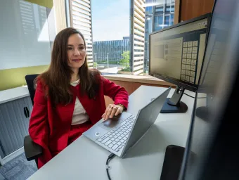 Dr Larisa Yarovaya working at her desk with laptop and monitors in an office.