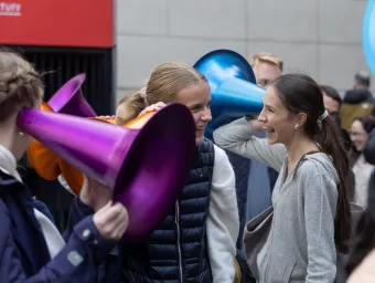 Students using large coulourful ear trumpets in an indoor science event.