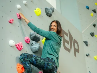 A climber on a climbing wall with coloured climbing holds.