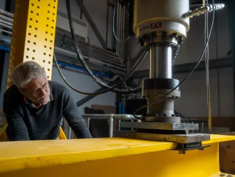 Professor David Richards inspecting a steel beam during laboratory testing.
