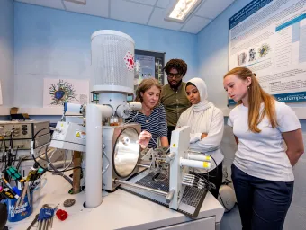 Students gather round a demonstration of a complicated medical imaging machine