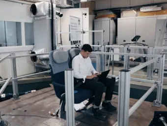 Passenger seated on a train seat mounted on a motion simulator used for vibration testing in the VibSim laboratory