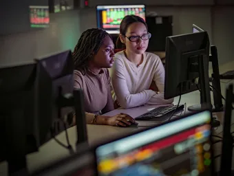two students seated in front of a computer monitor
