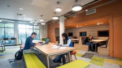 Students working at large shared table in a modern common room.