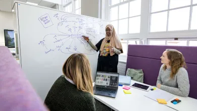 3 students in a common learning space, gathered around a whiteboard showing a mind map they are using to capture and organise their thoughts.
