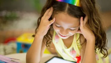 A young girl studies a tablet screen at a table