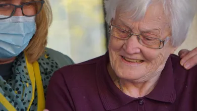 Elderly grey-haired woman with a masked carer
