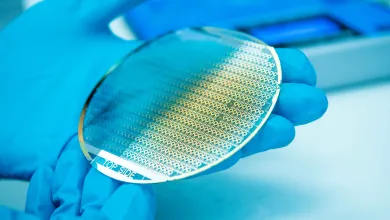 Pair of gloved hands holding a silicon disc chip