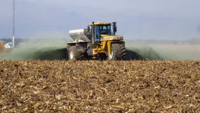 A tractor scattering crushed rock as it drives across a field.