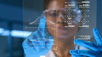A researcher wearing blue medical gloves scrolls data on a screen