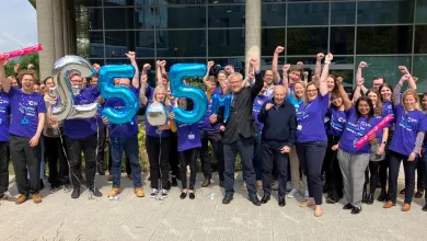 Southampton clinical trials unit researchers and staff outside their building, holding balloons saying £5.5 million