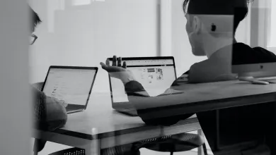 People working on laptops, seen through glass