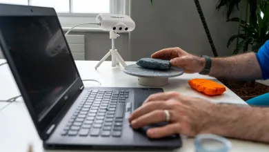 Open laptop on a desk with an unseen user, bar their wrists, operating the keyboard.